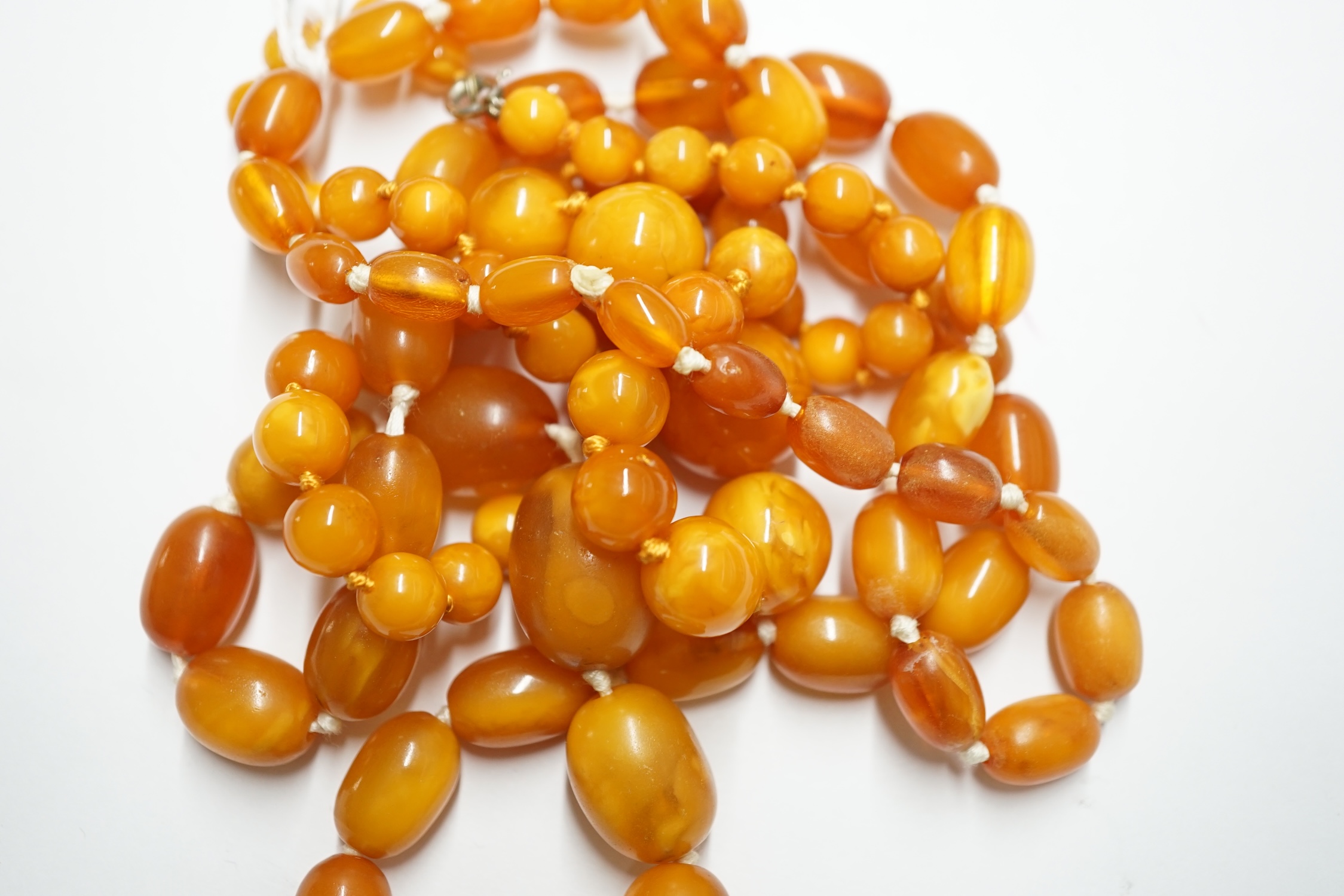 Two single strand graduated oval amber bead necklaces, longest 72cm, gross weight 63 grams. Condition - poor to fair